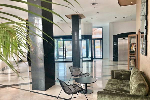 Eingangsbereich eines Hotels mit Sofa und Stühlen vor einer großen Glastür.
