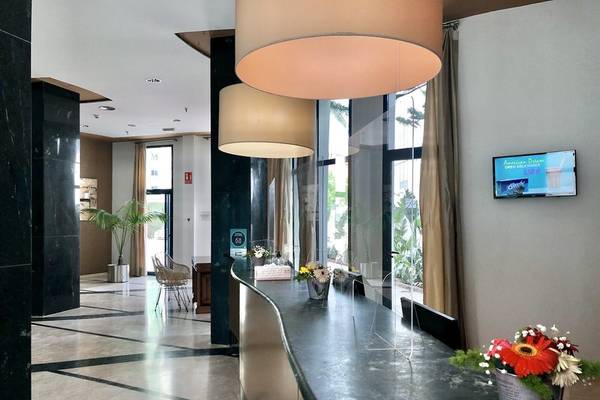 Empfangstresen im Eingangsbereich des Principal Afilliated by RH Hotels mit Blumen und Dekor.