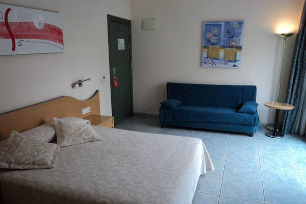 Schlafzimmer mit einem Bett, einem Sofa, einem Nachttisch und Wanddekorationen.