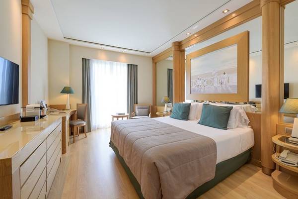 Innenansicht eines modernen Hotelzimmers im Las Arenas Balneario Resort mit einem großen Bett, einem Schreibtisch und einer gemütlichen Einrichtung.
