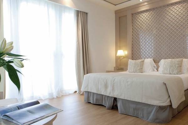Schlafzimmer im Las Arenas Balneario Resort Hotel mit großem Bett und weißen Möbeln.