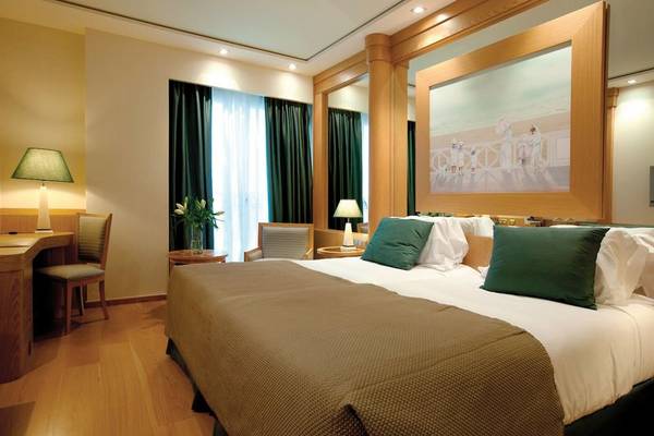 Hotelzimmer im Las Arenas Balneario Resort mit einem Bett, zwei Nachttischen, einem Schreibtisch, zwei Lampen und einem großen Gemälde.