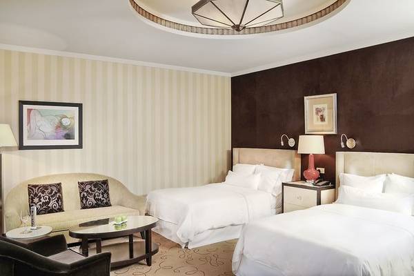 Schlafzimmer im Westin Valencia Hotel mit zwei Betten, einem Sofa und einer Kommode.