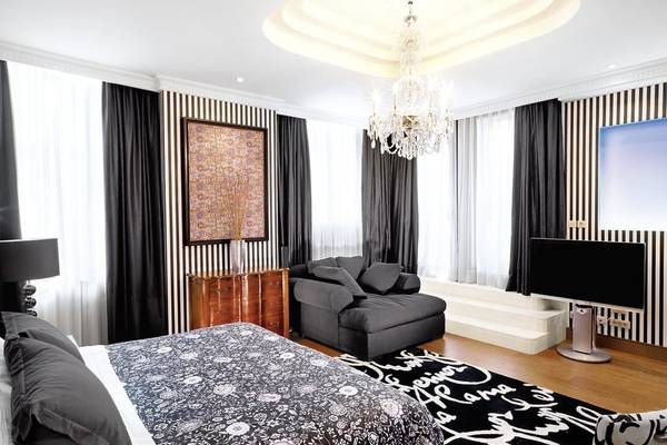 Schlafzimmer im Westin Valencia Hotel mit einem Bett, Sofa, Fernseher, Lampen und Kunstwerk.