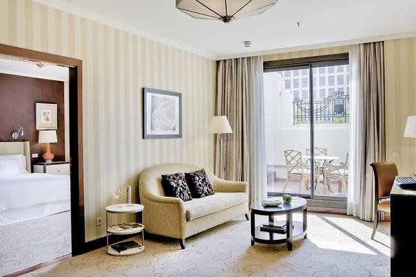 Hotelzimmer im Westin Valencia mit Sofa, Tisch, Fernseher und Balkon.