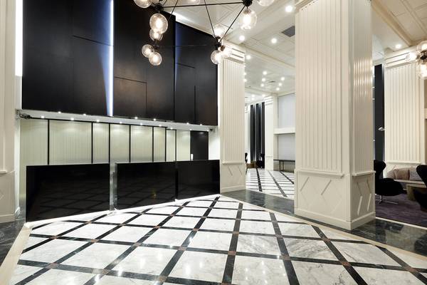 Lobby des Exe Rey Don Jaime Hotels mit schwarzen und weißen Wänden, Marmorboden und Kronleuchter.