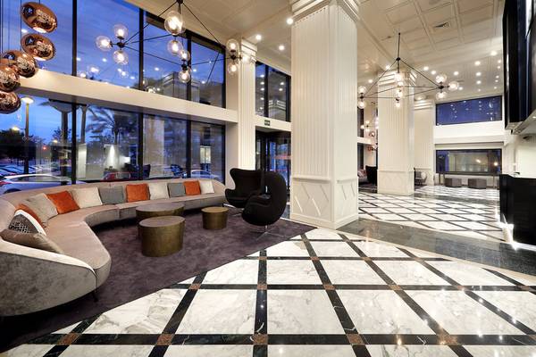 Lobby des Exe Rey Don Jaime Hotels mit Marmorboden, Couch, Kronleuchtern und Glaswänden.
