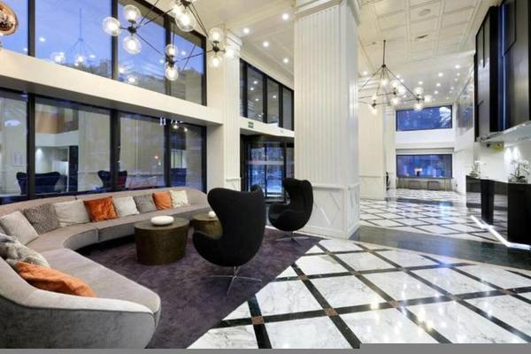 Lobby des Exe Rey Don Jaime Hotels mit großen Fenstern, einer Couch, schwarzen Stühlen und Marmorboden.