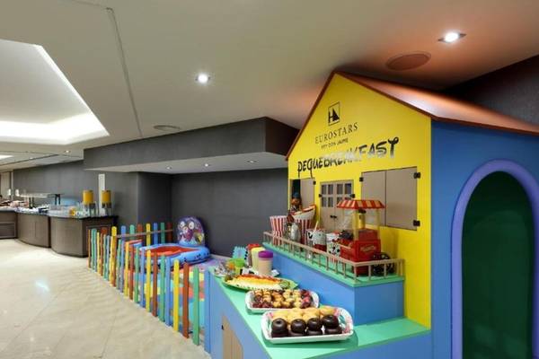 Kinderfrühstück im Exe Rey Don Jaime Hotel mit bunten Gebäuden und Essenstischen