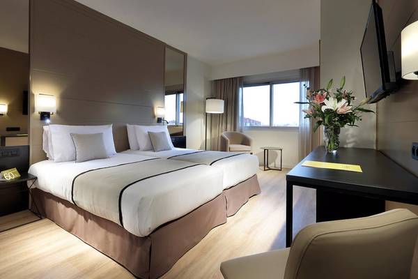 Doppelbett-Zimmer im Exe Rey Don Jaime Hotel mit Blumenvase und Fernseher.