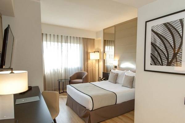 Ein elegantes Hotelzimmer mit Doppelbett, Schreibtisch, Stuhl und Lampe.