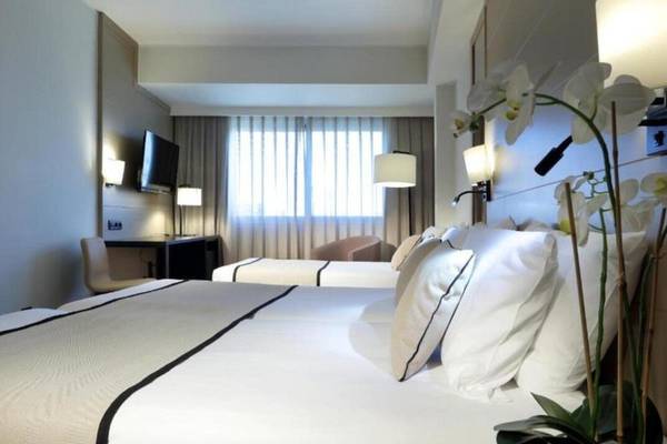 Hotelzimmer im Exe Rey Don Jaime mit zwei Betten, Fernseher und Dekor.