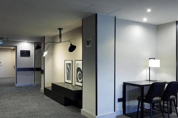 Lobbybereich des Exe Rey Don Jaime Hotels mit einem Tisch, Stühlen und Kunstwerken an der Wand.