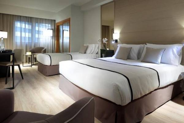 Schlafzimmer im Exe Rey Don Jaime Hotel mit zwei Betten, Dekor und Möbeln.