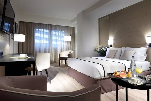 Ein modernes Hotelzimmer mit einem Bett, Schreibtisch, Stühlen und einem Frühstückstablett.