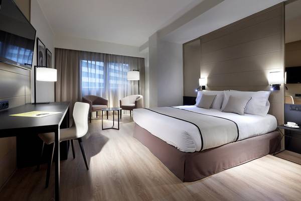 Innenansicht eines Hotelzimmers im Exe Rey Don Jaime, mit Bett, Schreibtisch und Stühlen.