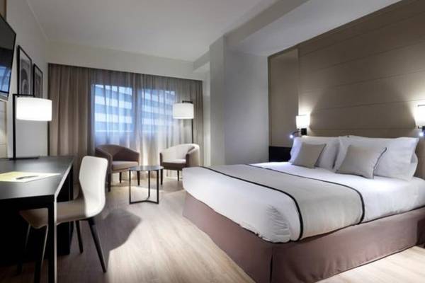 Hotelzimmer im Exe Rey Don Jaime mit Doppelbett, Schreibtisch und Sesseln.