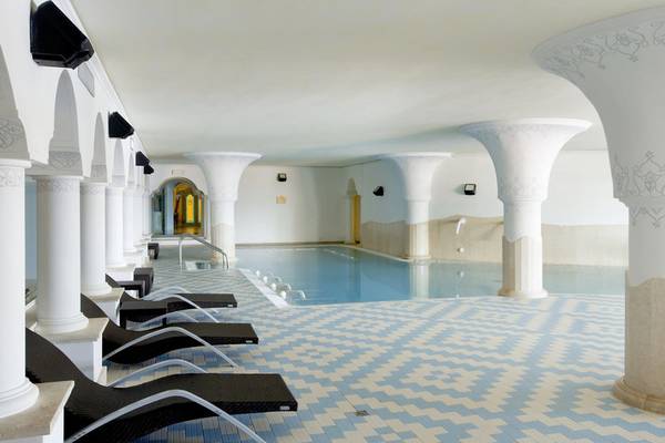 Innenpool des Almar Timi Ama Resort & Spa mit weißen Säulen und blauem Boden.