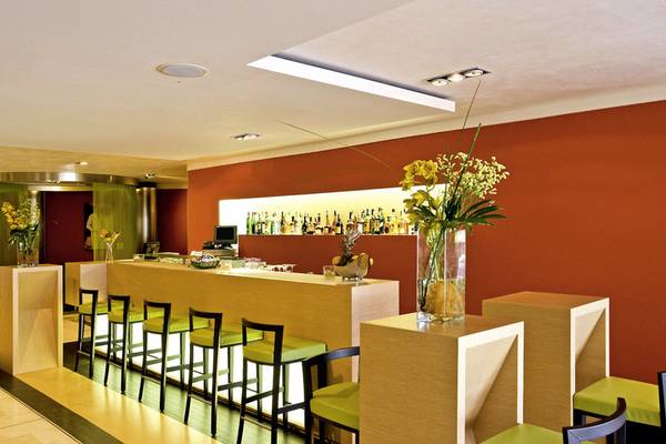 Barbereich im Almar Timi Ama Resort & Spa mit orangefarbenen Wänden und grünen Stühlen.