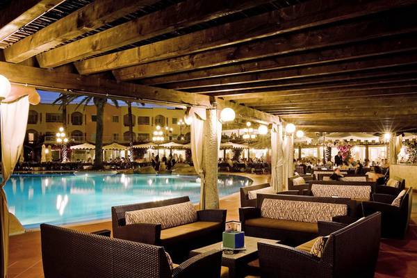 Pool-Lounge im Almar Timi Ama Resort & Spa mit braunen Sofas und einem Swimmingpool.