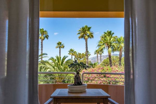 Blick von einem Balkon des Almar Timi Ama Resorts auf eine Gruppe von Palmen und Berge.