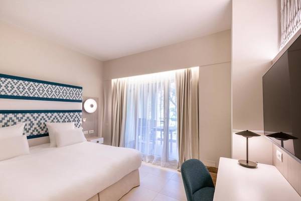 Ein modernes Hotelzimmer im Almar Timi Ama Resort & Spa mit einem Bett, einem Schreibtisch und einem Fernseher.