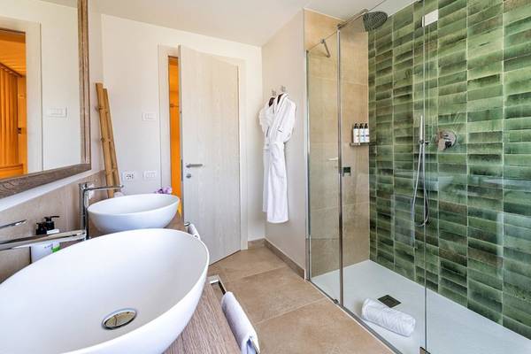 Badezimmer im Almar Timi Ama Resort & Spa mit zwei Waschbecken und einer grünen gefliesten Dusche.