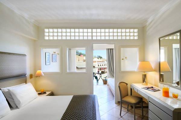 Innenansicht eines Zimmers im Lindos Royal Resort mit Bett, Schreibtisch und Balkon
