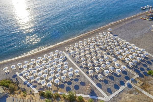 Luftaufnahme des Strandes mit vielen Sonnenschirmen und Stühlen im Lindos Royal Resort.