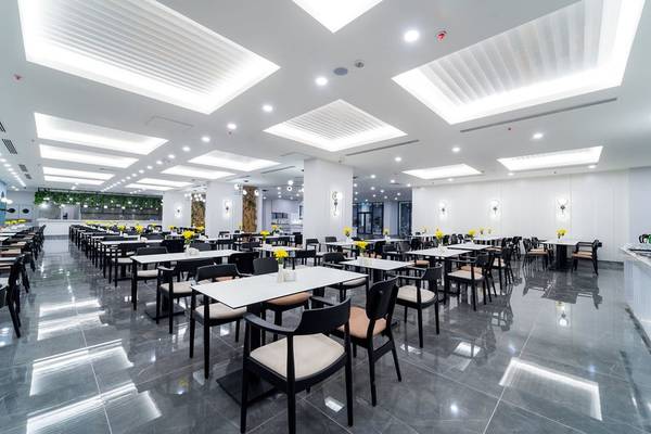 Restaurant im Arcanus Hotels Trendline Side mit weißen Tischen, gelben Blumen und moderner Beleuchtung.
