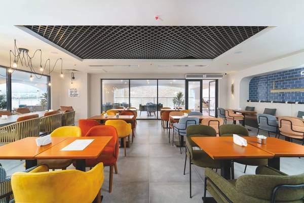 Innenansicht des Restaurants im Arcanus Hotels Trendline Side mit bunten Stühlen und Tischen.