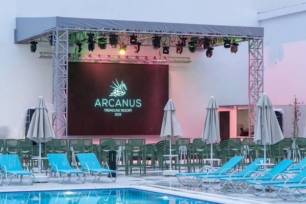 Ein Poolbereich des Arcanus Hotels Trendline Side mit einer Bühne und Loungestühlen.