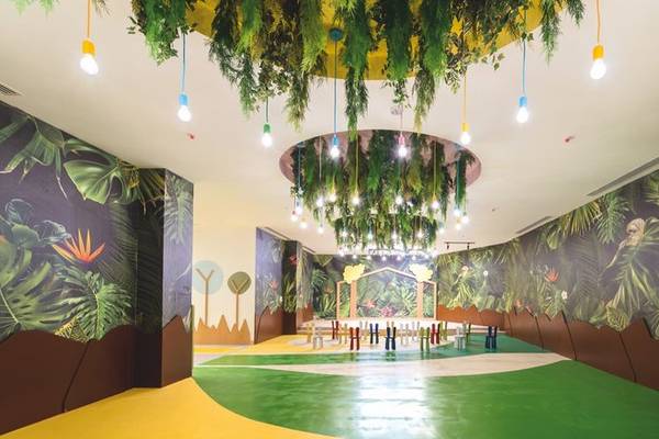 Ein kinderfreundliches Zimmer mit grünen und gelben Böden, bunten Wandmalereien und einer Lichterkrone.