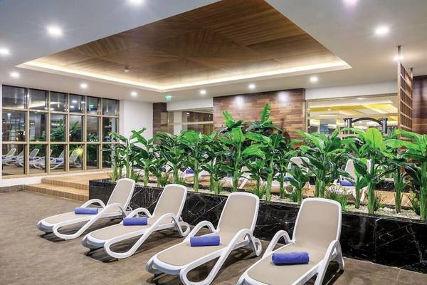 Loungebereich im Sunis Efes Royal Palace Resort & Spa mit weißen Liegen und grünen Pflanzen.