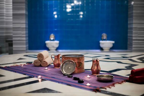 Spa-Bereich des Sunis Efes Royal Palace Resorts mit Kupfergefäßen, Kerzen und Steinen auf einem Teppich.
