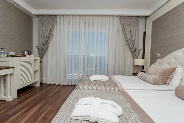 Doppelzimmer im Sunis Efes Royal Palace Resort & Spa mit zwei Betten, Aussicht und luxuriöser Einrichtung.