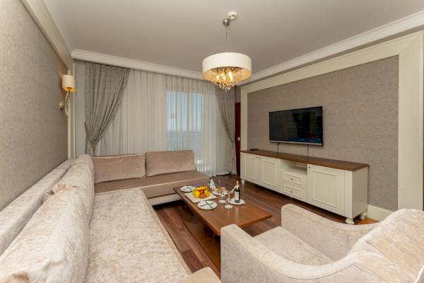 Wohnzimmer im Sunis Efes Royal Palace Resort & Spa mit Sofas, Tisch und Fernseher.