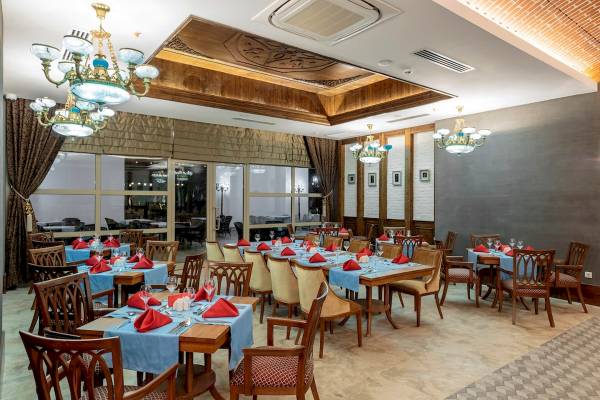 Restaurant im Sunis Efes Royal Palace Resort & Spa mit gedeckten Tischen und Kronleuchtern.