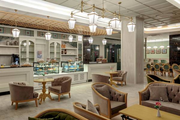 Hotel-Lounge-Bereich mit Möbeln, Tischen, Stühlen und Deckenleuchten.