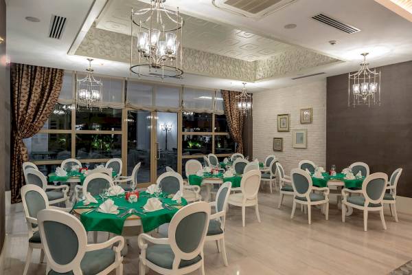 Innenansicht des Restaurants im Sunis Efes Royal Palace Resort & Spa mit runden Tischen und Stühlen.