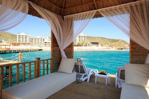 Terrasse des Sunis Efes Royal Palace Resorts mit Blick auf das Meer und das Hotelgebäude.