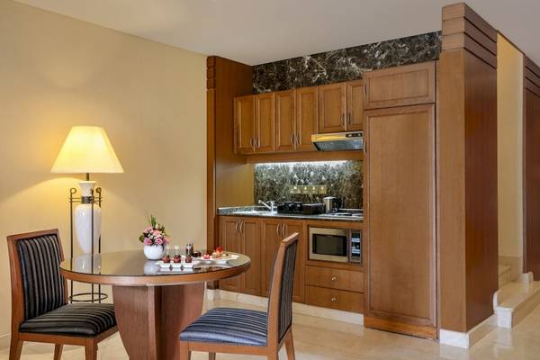 Küche im Al Ain Rotana Hotel mit Tisch, Stühlen und Mikrowelle