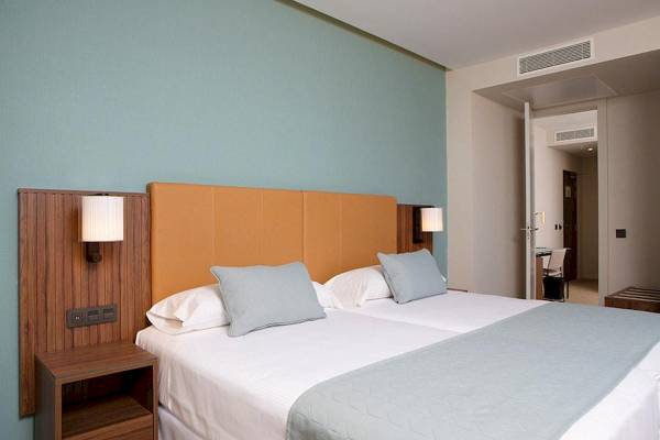 Doppelbett-Zimmer im Riu Plaza Espana Hotel mit blauen Wänden und Nachttischen.