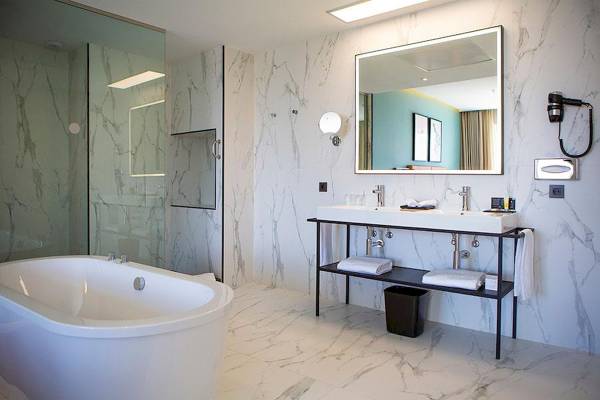 Ein Badezimmer im Riu Plaza Espana Hotel mit Badewanne, Waschbecken und Spiegel.