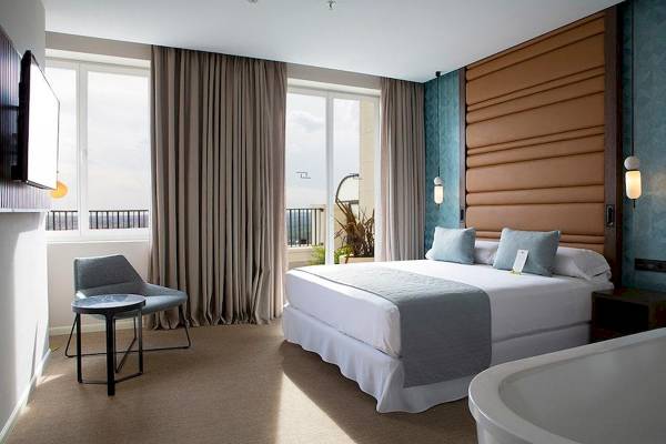 Innenansicht eines Hotelzimmers im Riu Plaza Espana mit Doppelbett, Balkon und moderner Einrichtung.