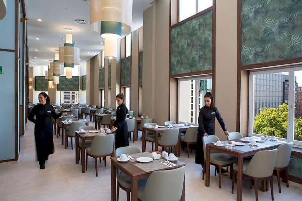 Restaurant im Riu Plaza Espana mit drei Kellnerinnen und gedeckten Tischen