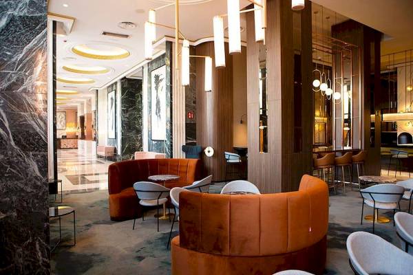 Lobby des Riu Plaza Espana Hotels mit orangefarbenen Sofas, Tischen und Kronleuchtern.