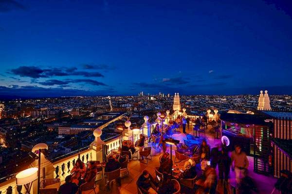 Abendlicher Ausblick auf das Hotel Riu Plaza Espana mit beleuchteter Stadt im Hintergrund.