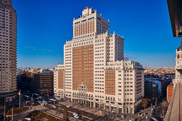 Außenansicht des Riu Plaza Espana Gebäudes mit vielen Fenstern und Stadt im Hintergrund.