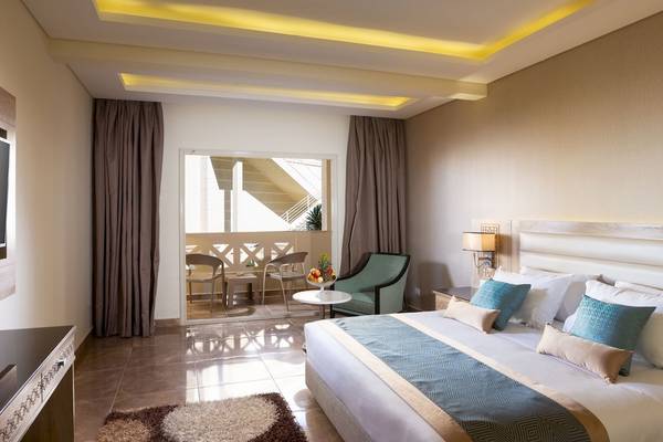 Innenansicht eines Hotelzimmers im Pickalbatros Aqua Blu Resort in Hurghada mit Bett, Tisch und Balkon.